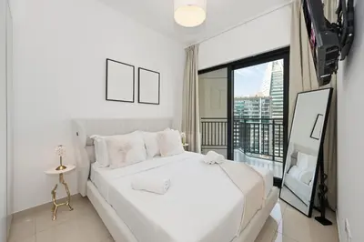 a white bedroom with a large bed and a balcony at Zada 1BR High Floor - Stunning View 1min Downtown and 2min to Metro in Dubai