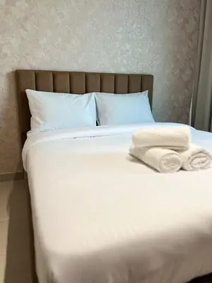 a bed with white sheets and two towels on it at Elegant Studio Stay in Binghatti Tulip Dubai in Dubai