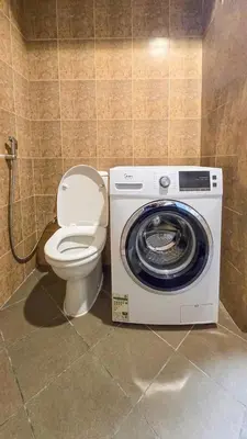 a bathroom with a toilet and a washing machine at Stylish Dubai Stay in Dubai
