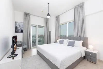 a bedroom with a white bed and large windows at Deluxe Ensuite Room with Balcony & Twin Beds in Dubai