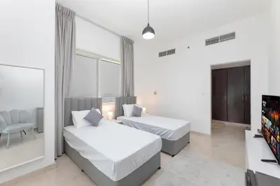 a hotel room with two beds and a television at Deluxe Ensuite Room with Balcony & Twin Beds in Dubai