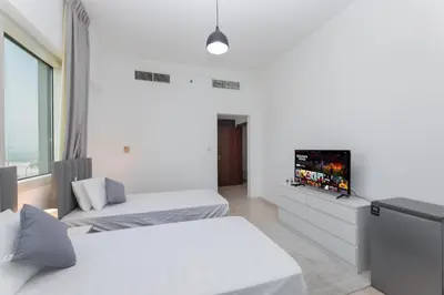 a white room with two beds and a flat screen tv at Deluxe Ensuite Room with Balcony & Twin Beds in Dubai