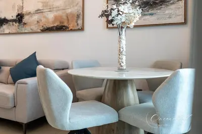 a table with chairs and a vase with flowers on it at Cool 1BR with Balcony in Marina, Steps from Metro in Dubai