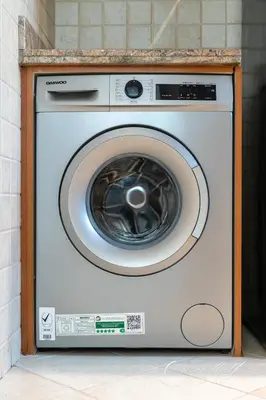 a washing machine in a wooden frame in a kitchen at Cool 1BR with Balcony in Marina, Steps from Metro in Dubai