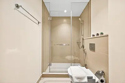 a bathroom with a shower with a toilet and a sink at Golden Stays - Stunning Downtown 2Br with Full Burj Views & Free Parking in Dubai