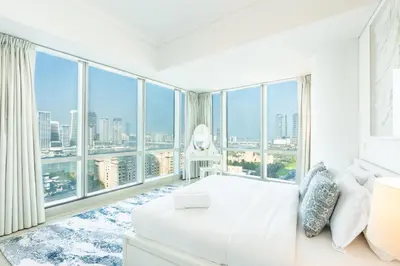 a bedroom with a white bed and large windows at RH- Marina Living- Chic Ocean Heights 3BR with Panoramic Views in Dubai