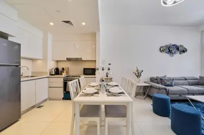 a kitchen and living room with a white table and chairs at fam Living Chic 1BR Retreat in Dubai Hills Estate in Dubai