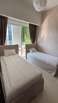 two beds in a hotel room with a window at Mama's Crib Dubai in Sabkhah