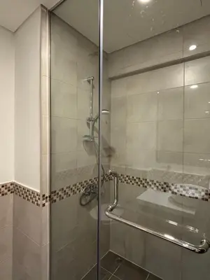 a bathroom with a glass shower with a sink at Mama's Crib Dubai in Sabkhah
