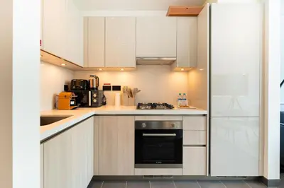 a kitchen with white cabinets and a stove at HAVN - 1 bedroom in The Crest, Skyline Views in Dubai
