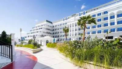 a large white building with palm trees in front of it at Vincitore Benessere - Arjan by Golden Casa in Dubai
