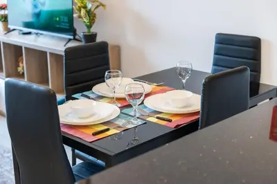 a dining table with glasses and plates on it at StayShort - Stunning 2BR Apartment in Jebel Ali Village in Dubai
