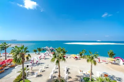 a beach with palm trees and chairs and the ocean at voco Dubai Nice The Heart of Europe by IHG in Dubai