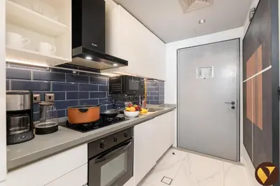 a kitchen with white cabinets and blue tiles at Vogue Downtown Mag 318 near Burj Khalifa and Dubai Mall, Studio Apartment with Balcony and City View, Access to all Amenities in Dubai