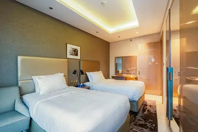 a hotel room with two beds and a couch at Venetian - High Floor 2BR Residence with Incredible Burj View in Dubai