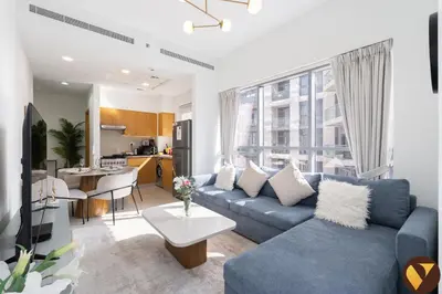 a living room with a blue couch and a kitchen at Vogue Downtown Bellevue Towers near Burj Khalifa and Dubai Mall, One Bedroom Apartment with City View, Full Access to all Amenities in Dubai