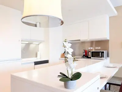 a white kitchen with a plant on a counter at 1BR Apt Kempinski Central Avenue Downtown Dubai in Dubai