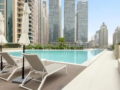 a balcony with chairs and a swimming pool on a building at Luxury 1BR in LIV Marina with Canal Views in Dubai