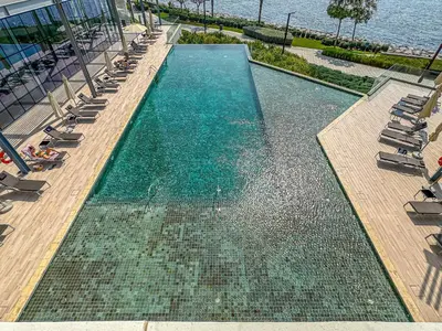 an empty swimming pool with lounge chairs and the water at Mira Holiday Homes - Sky High Bliss at Bluewaters Residence 3 Ain View in Dubai