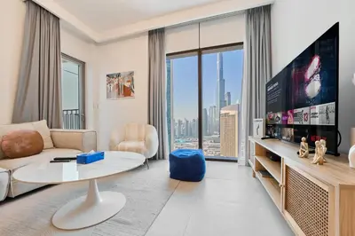 a living room with a couch and a tv at Stunning 2BR Skyline Stay With Full Burj Khalifa View in Dubai