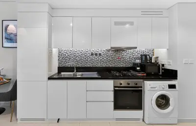 a white kitchen with a sink and a dishwasher at Dubai Business Bay Luxurious Studio with Canal View and access to Lagoon Pool in Dubai
