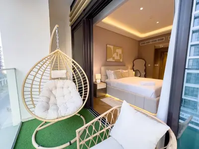 a room with a hammock on a balcony with a bed at Meydan Luxury Stylish 2BR with Pool & City Views in Dubai