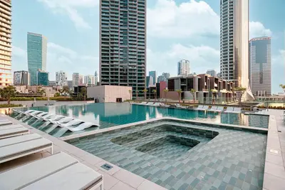a swimming pool with chairs and a city skyline at StayMada - Peninsula Luxury Apartment with Balcony in Dubai