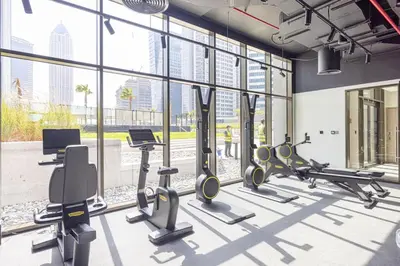 a gym with treadmills and cardio equipment in a building at StayMada - Peninsula Luxury Apartment with Balcony in Dubai