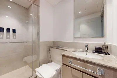 a bathroom with a shower and a sink and a mirror at Locations I Downtown Dubai I Premium 3BR Apartment I Luxury & Modern Interiors I Stunning Burj Khalifa Views I Steps from Dubai Mall & Dubai Fountain in Dubai