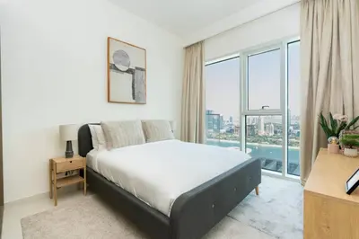 a bedroom with a bed and a large window at CitiHome - Elie Saab Luxury 2BR - Sea View in Dubai
