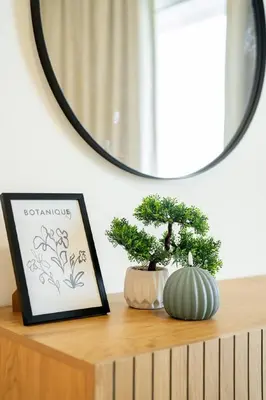 a mirror above a shelf with two bonsai trees on it at CitiHome Luxury Stay Panoramic Sea Views 2BR in Dubai