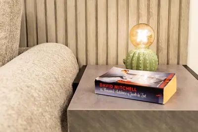 a book and a lamp on a table next to a couch at 1BR with Burj Khalifa view in Business Bay in Dubai