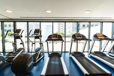 a row of treadmills in a gym with windows at 1BR with Burj Khalifa view in Business Bay in Dubai