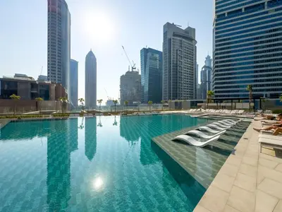 a large swimming pool in a city with tall buildings at Waterfront 1BR with Canal Views in Peninsula One in Dubai