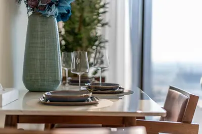 a table with plates and glasses and a vase at Waterfront 1BR with Canal Views in Peninsula One in Dubai