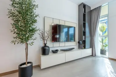 a living room with a tv and a potted tree at Balcony with Panoramic Dubai Water Canal and City Views, Walking Distance to Metro and Marine Transport, Urban Oasis, Business Bay by Deluxe Holiday Homes in Dubai