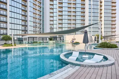a swimming pool with two chairs and a large building at STAY BY LATINEM Luxury 1BR Holiday Home CC 2913 Near Burj Khalifa in Dubai