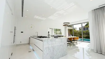 a white kitchen with a counter and a dining table at Premium Sidra Villa with Private Pool and Exclusive Stay in Dubai