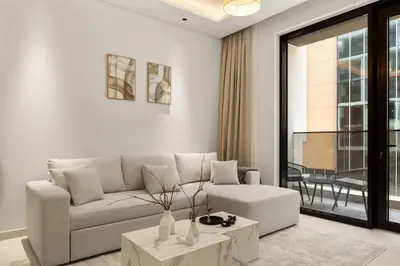 a white living room with a couch and a table at Brand New 2BR, Circle Mall View, Great Pool & Gym in Dubai