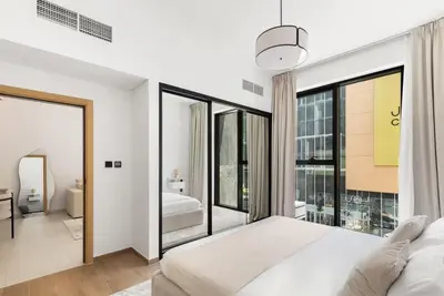 a bedroom with a bed and a large window at Brand New 2BR, Circle Mall View, Great Pool & Gym in Dubai