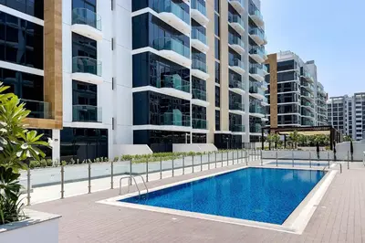 a swimming pool in front of a tall building at Stylish Studio in Nad Al Sheba in Dubai