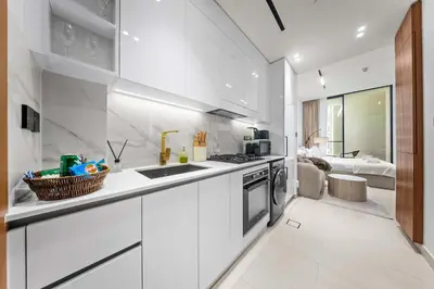 a white kitchen with a sink and a stove at Brand New Luxury Studio, Amazing Pool & Gym in Dubai