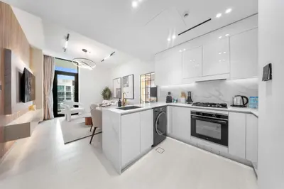 a kitchen with white cabinets and a dining room at Chic 1BR Getaway, Sleeps 4, Stunning Pool Views in Dubai