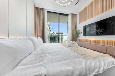 a large white bed in a bedroom with a large window at Chic 1BR Getaway, Sleeps 4, Stunning Pool Views in Dubai