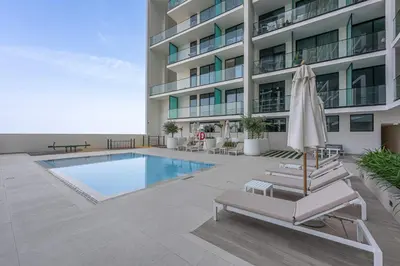 a hotel with a swimming pool and two lounge chairs and an umbrella at Chic 1BR Getaway, Sleeps 4, Stunning Pool Views in Dubai