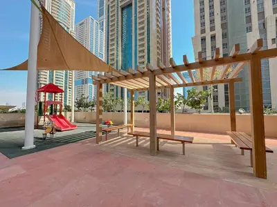 a playground with benches and a play structure in a city at TRPS - Elite Residence, Dubai Marina - Modern High-Rise, Near Popular Sites, Partial Sea View in Dubai