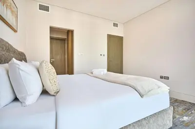 a white bedroom with a large bed with white pillows at Newly Furnished Apt in District 1 in Dubai