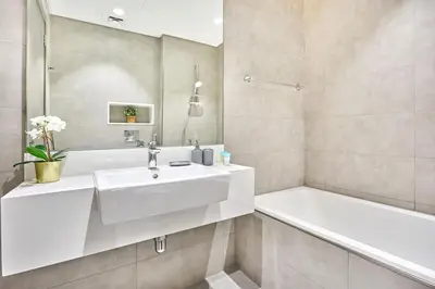a white bathroom with a sink and a tub at Newly Furnished Apt in District 1 in Dubai
