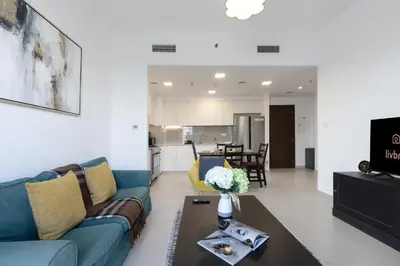 a living room with a blue couch and a table at 2BR in Safi Balcony Walk to Town Sq Park in Dubai