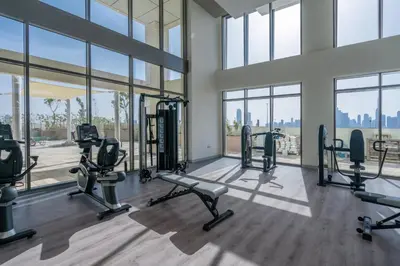 a gym with treadmills and ellipticals in a building with windows at GuestReady - Sunny Retreat near Dubai Frame in Dubai